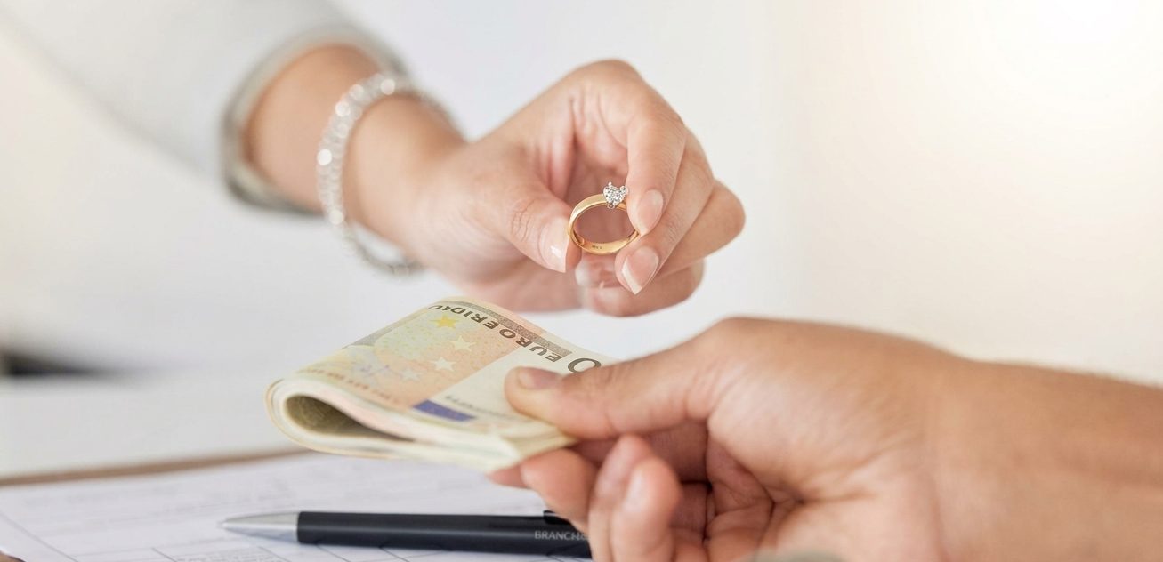Gold ring exchanged for cash across a counter, representing a gold loan